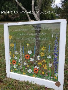 a sign in the grass with flowers painted on it