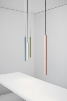 three different colored lights hanging from the ceiling in a room with white walls and flooring