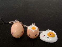 three necklaces with eggs and an egg in the shape of two heads on a black surface