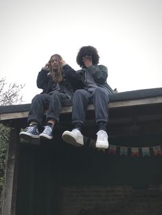 two people sitting on top of a roof