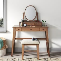 a dressing table with a mirror, stool and plant on it in front of a window