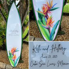 the surfboard has been painted with flowers and birds of paradise on it's side