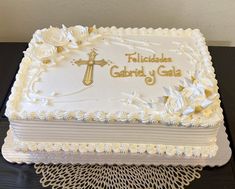 a cake with white frosting and gold lettering on it sitting on a doily