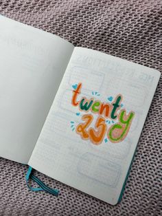 an open notebook with the words twenty forty written in colorful lettering on it, sitting on a gray surface