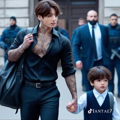 a man with tattoos walking next to a little boy wearing a suit and tie on the street