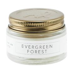 evergreen forest candle in a glass jar with a gold lid and white label on the front