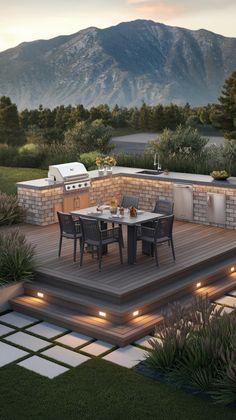 an outdoor kitchen and dining area is lit up at night with mountains in the background