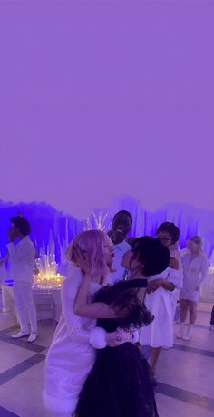 two women hugging each other in front of an audience at a wedding reception with purple lighting behind them