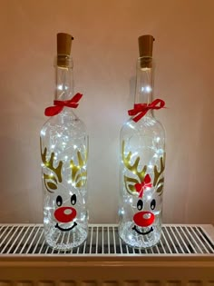 two glass bottles decorated with lights and reindeer heads are sitting on a shelf next to each other