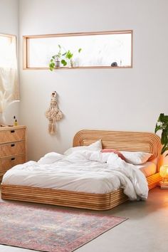 a bed with white sheets and pillows in a room next to a dresser, lamp and window