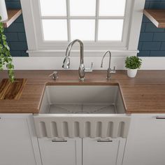 a white kitchen sink sitting under a window next to a counter top with a potted plant