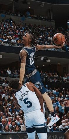 a basketball player jumping up to dunk the ball in front of an audience at a sporting event