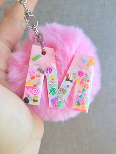 a pink furry keychain with the letter v on it's front and bottom