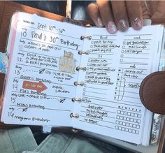 a person holding a planner in their hand with writing on the pages and numbers inside it