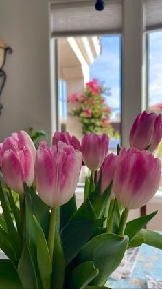 some pink tulips are in a vase on a table