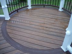 a wooden deck with white railings and pillars