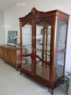 an antique china cabinet with glass doors in a living room area, showing the top section and bottom section