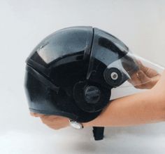 a hand holding a black motorcycle helmet with clear visor