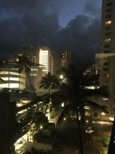 the city is lit up at night with palm trees in the foreground and buildings on the other side