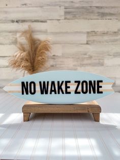 a surfboard with the words no wake zone on it sitting on a wooden stand