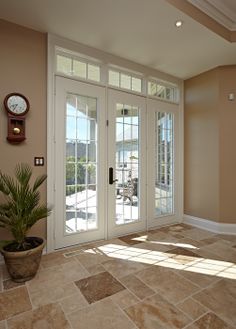 a room with two doors and a clock mounted on the wall above it's glass door