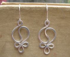 two silver earrings sitting on top of a piece of cloth