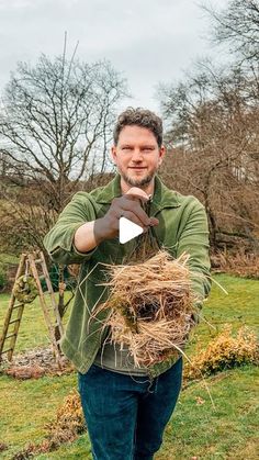 a man standing in the grass holding a bird's nest