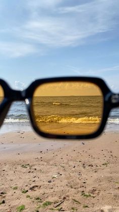 a pair of sunglasses sitting on top of a sandy beach