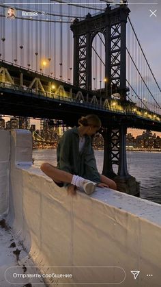 a man sitting on top of a wall next to a bridge