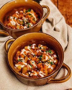 two brown bowls filled with food sitting on top of a cloth covered table next to each other