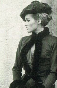 an old photo of a woman wearing a hat and coat with fur trimmings