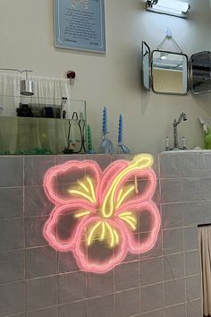 a neon flower is on the wall next to a sink