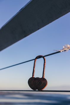 a heart shaped padlock attached to the side of a boat with water in the background