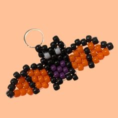 an orange, black and white beaded keychain on a pink background with space for text