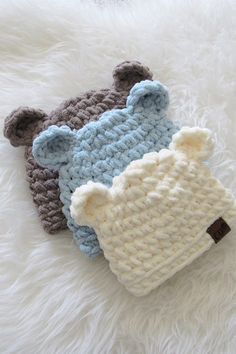 two knitted teddy bears laying on top of white fur