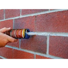 a person spraying water onto a brick wall with a spray bottle attached to the side