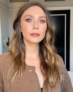 a woman with long hair and blue eyes is posing for the camera in front of a mirror