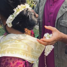 a man and woman standing next to each other holding flowers in their hands while another person holds out his hand