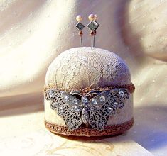 a white hat with pearls and lace on it sitting on a cloth covered tablecloth