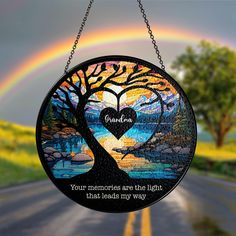 a stained glass sun catcher with a rainbow in the background and a tree on it