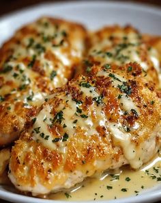 two pieces of chicken covered in gravy on top of a white plate with parsley