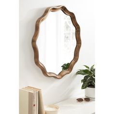 a mirror sitting on top of a white table next to a potted plant and book