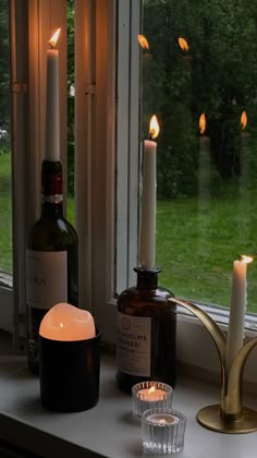 candles and bottles are sitting on a window sill