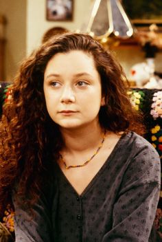 a woman with long curly hair sitting on a couch