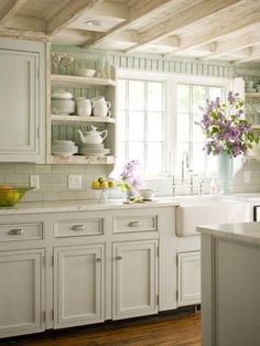 a kitchen filled with lots of white cupboards and counter top next to a window