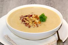 a white bowl filled with soup on top of a plate