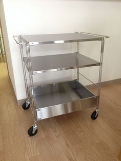 three tiered stainless steel serving cart with wheels on the floor in an empty room