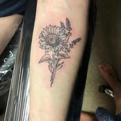 a black and white photo of a sunflower tattoo on the right arm, with lavenders in it