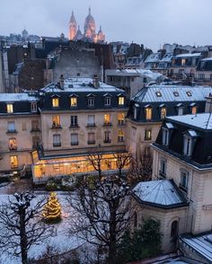 the city is lit up at night with christmas lights in the windows and snow on the ground