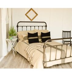 a metal bed frame with black and white pillows